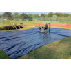 Équipe technique positionnant la bâche de protection au sol avant le montage de la tente stretch nomade.
