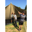 Équipe technique tendant les cordes de fixation lors du montage d'une tente stretch nomade.